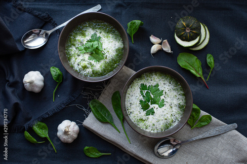 two plates of green creamy garlic soup. 