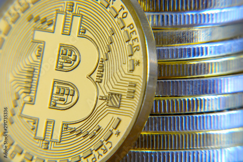 Close-up stack golden and silver cryptocurrencies together. Golden bitcoin in front of it.