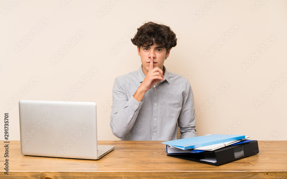 Young student man with a laptop showing a sign of silence gesture putting finger in mouth Young student man with a laptop showing a sign of silence gesture putting finger in mouth