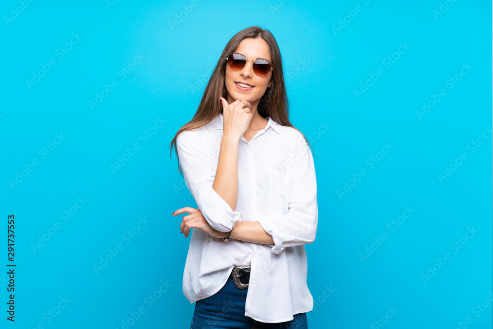Young woman over isolated blue background with glasses and smiling Young woman over isolated blue background with glasses and smiling