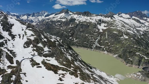 Aerial view of Grimsel Pass in Swiss Alps, picturesque scenery of snowy mountains and lake Grimselsee (hydroelectric reservoir) during spring thaw - landscape panorama of Switzerland from above,Europe photo