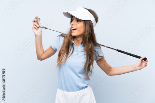 Young golfer woman over isolated blue wall © luismolinero