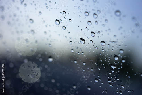 Abstract blurred Rain while the car is in the middle of the road at night Car tail light reflecting with rain drops on the car mirror