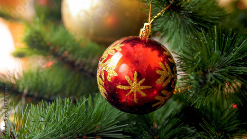 Closeup photo of red sparkling ball on beautiful Christmas tree. Perfect abstract background for winter holidays or celebrations