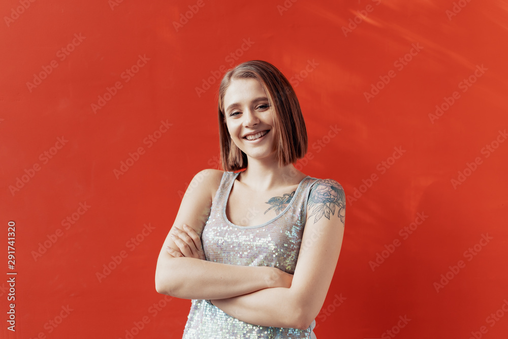 Fototapeta premium Cheerful young girl posing in front of a red wall