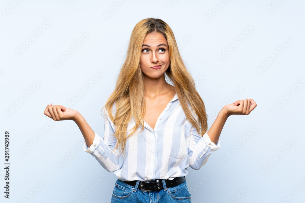 Young blonde woman over isolated blue background having doubts while raising hands Young blonde woman over isolated blue background having doubts while raising hands