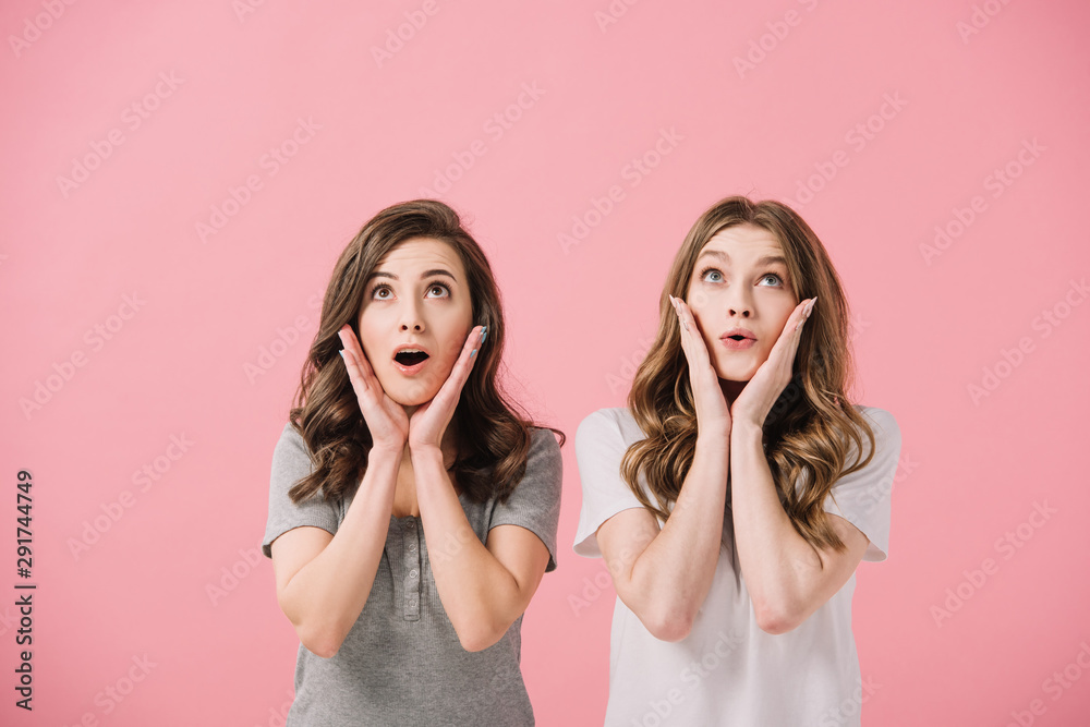 attractive and shocked women in t-shirts looking up isolated on pink attractive and shocked women in t-shirts looking up isolated on pink