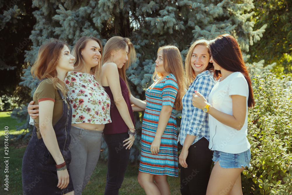 Obraz premium Different and happy in their bodies. Young women smiling, talking, walking and having fun together outdoors on sunny summer's day at park. Girl power, feminism, women's rights, friendship concept.