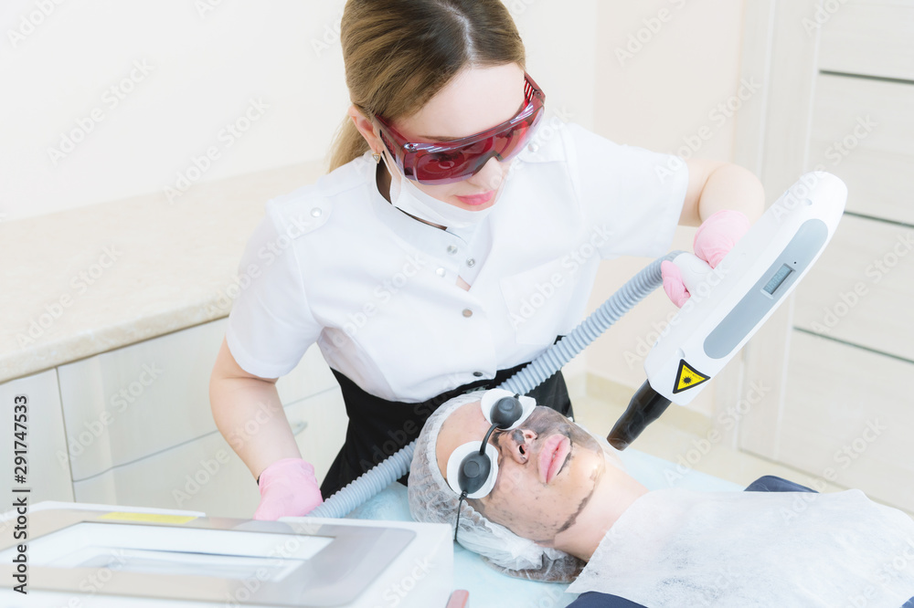 The cosmetician girl in goggles makes the procedure of carbon peeling with the help of a cosmetology laser. Carbon face peeling procedure. Laser pulses clean skin of the face.