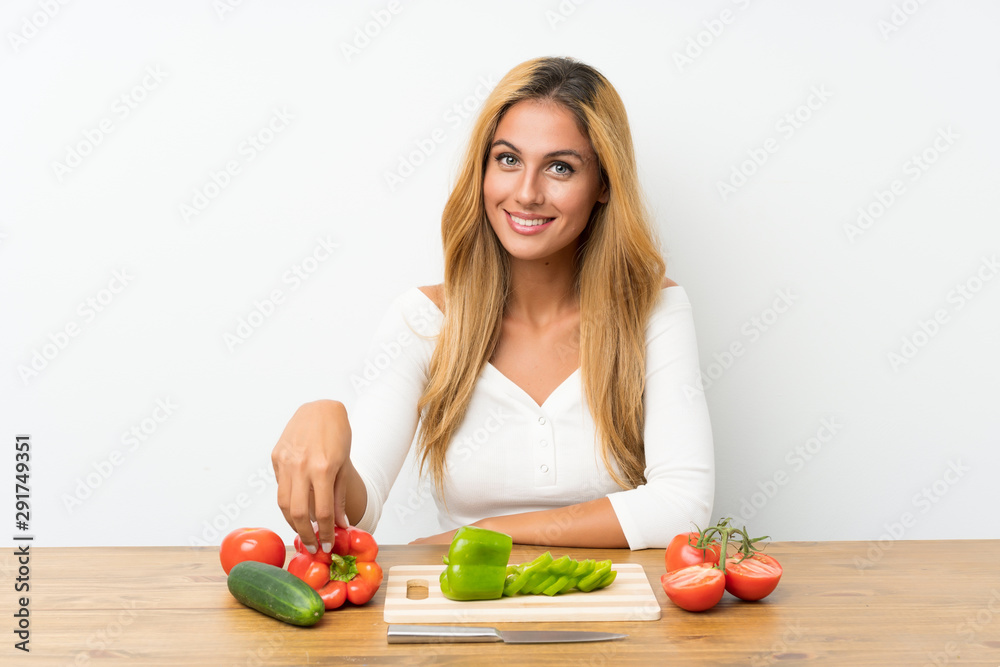 Young blonde woman with vegetables in a table Young blonde woman with vegetables in a table