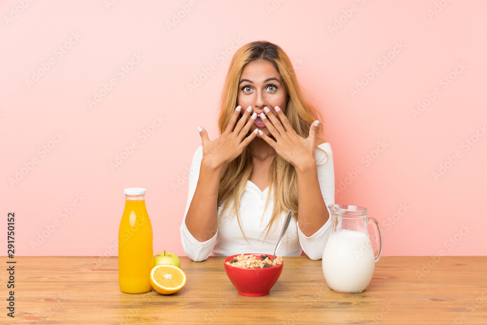 Young blonde woman having breakfast milk with surprise facial expression Young blonde woman having breakfast milk with surprise facial expression