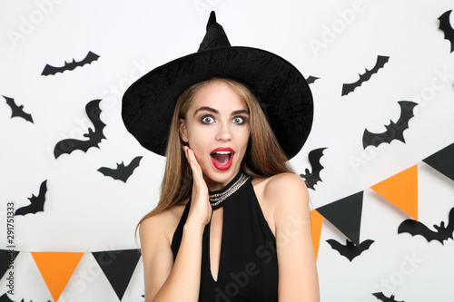 Beautiful woman in halloween costume with paper bats and flags on white background
