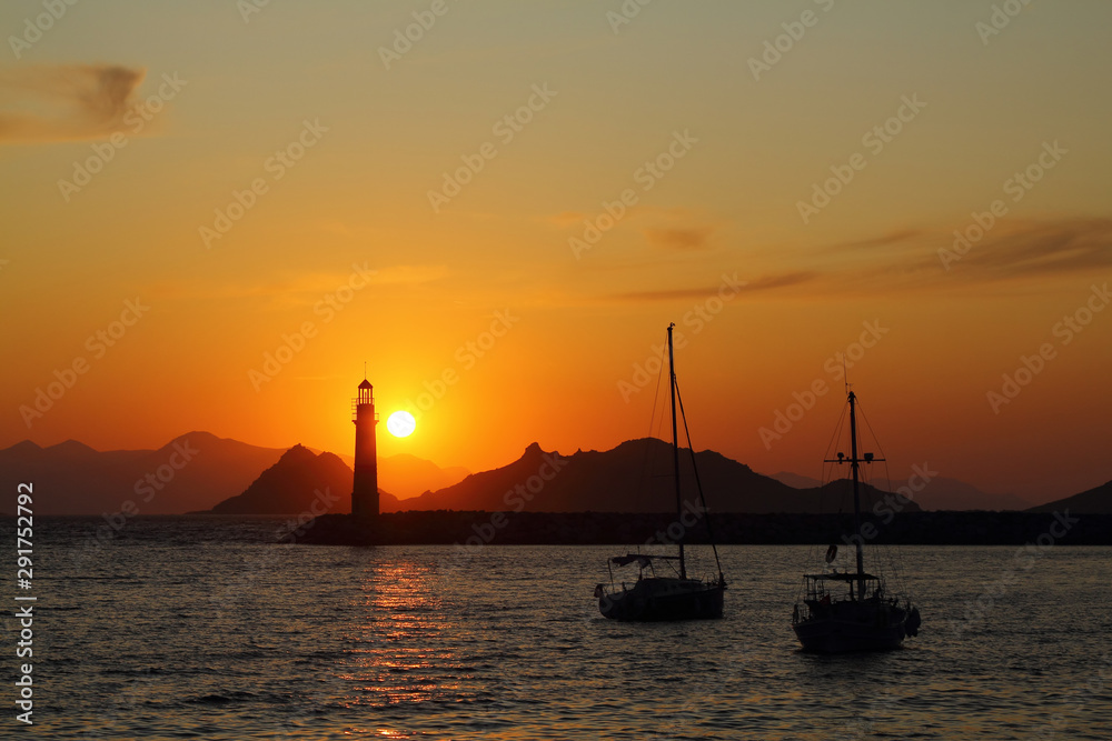 Seascape at sunset. Lighthouse on the coast. Seaside town of Turgutreis and spectacular sunsets