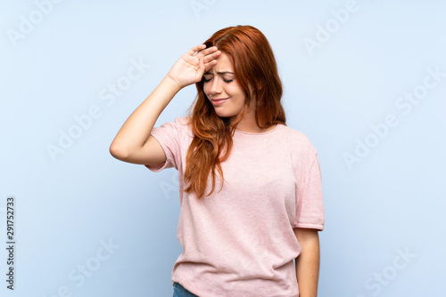 Teenager redhead girl over isolated blue background with tired and sick expression