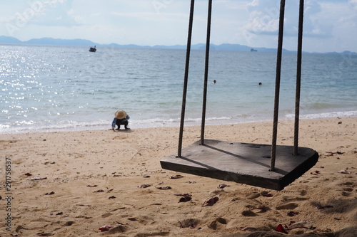 Swing on the beach And the sea in the background Someone is building sand piles.