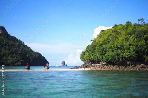 An island in the middle of the sea with a beach path across to another island 