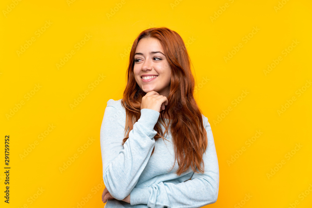 Teenager redhead girl over isolated yellow background looking to the side Teenager redhead girl over isolated yellow background looking to the side