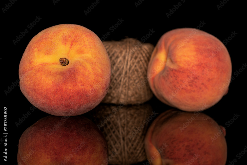 Group of two whole fresh fuzzy peach with spool isolated on black glass Group of two whole fresh fuzzy peach with spool isolated on black glass