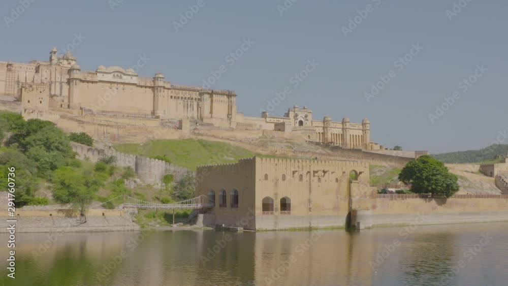 A daylight wide shot of the exterior facade of a large fortress made of concrete built above the hills beside a calm river. A daylight wide shot of the exterior facade of a large fortress made of concrete built above the hills beside a calm river.