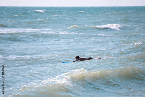 Man with surfboard swimming in the sea