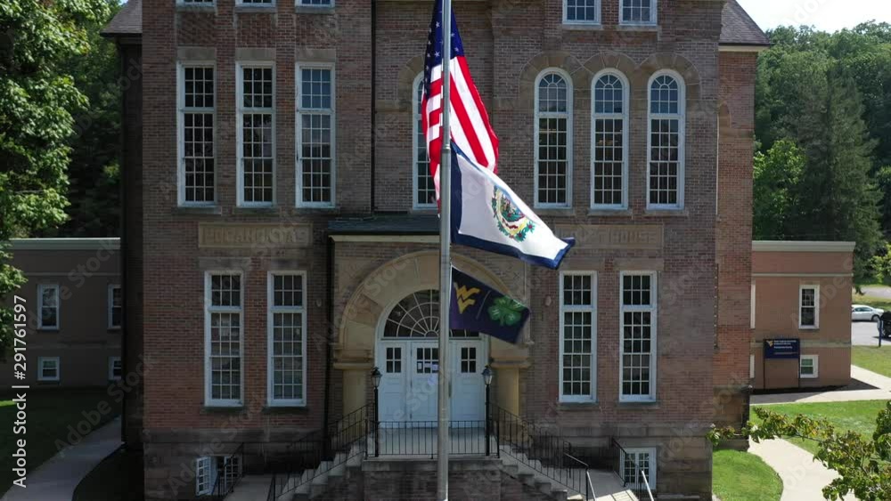West Virginia state flag with US Flag and WVU flag flying in front of the Pocahontas County Courthouse in Marlinton, West Virginia. West Virginia state flag with US Flag and WVU flag flying in front of the Pocahontas County Courthouse in Marlinton, West Virginia.