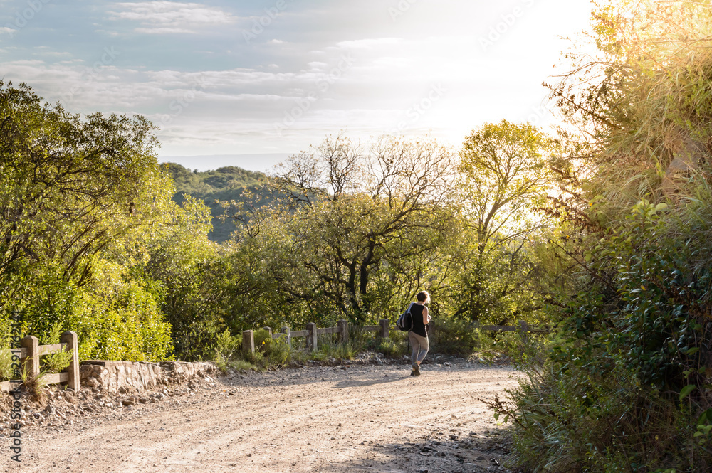 Joven mujer con mochila, caminando por las sierras de Córdoba en otoño Joven mujer con mochila, caminando por las sierras de Córdoba en otoño