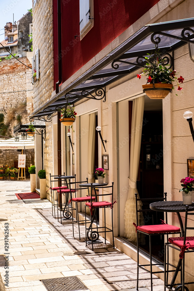 Picturesque narrow stone street with bars, tables, lantern in Roman town, summer time and holidays, Split, Dalmatia, Croatia 