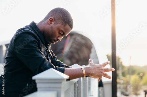 Man looking down with hands on railing 