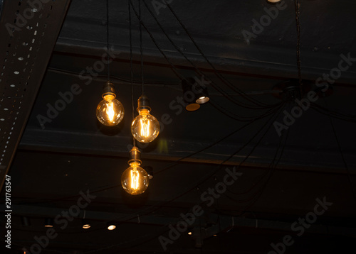 Lighting decor. Hanging Light Bulb in the dark room with copy space.