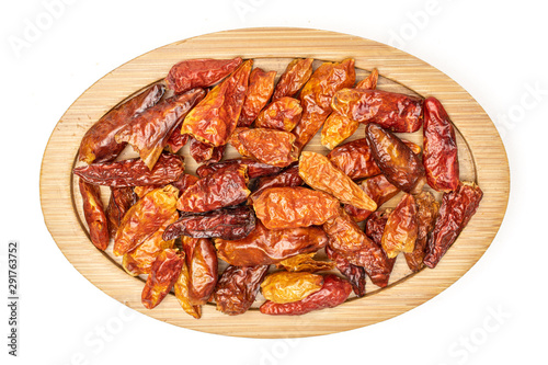 Lot of whole dry red chili pepper peperoncino on bamboo plate flatlay isolated on white background