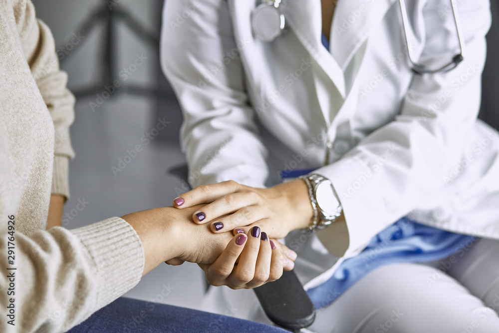 Obraz premium Woman doctor calms patient and holds hand