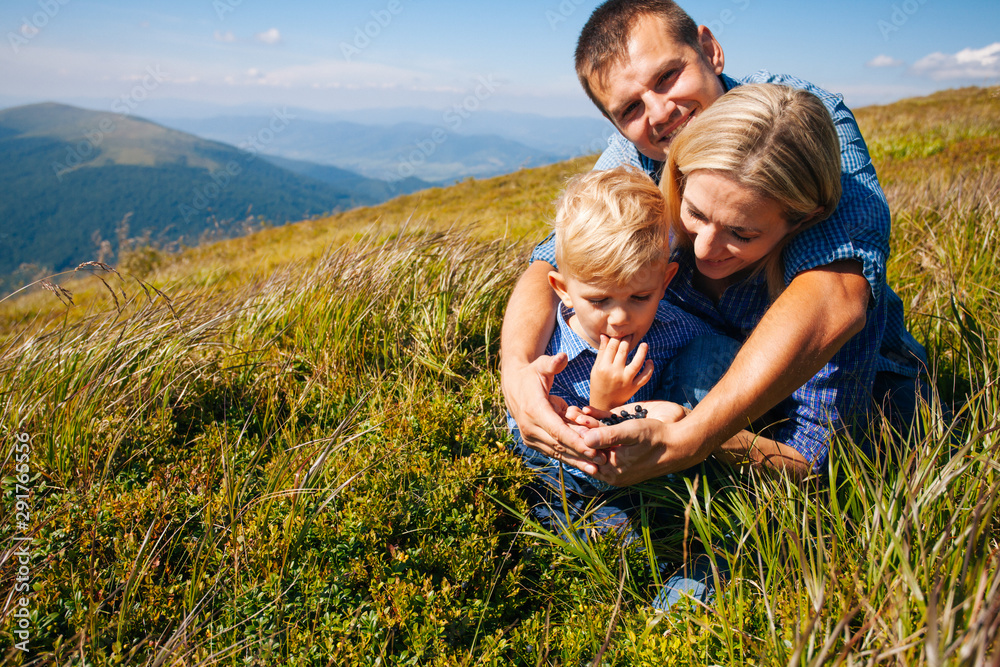 The family tastes wild berries on mountain hills The family tastes wild berries on mountain hills