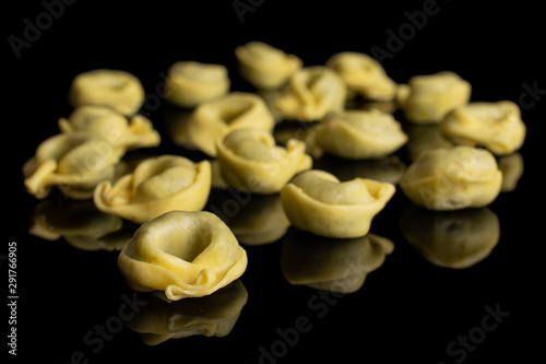 Lot of whole fresh yellow spinach filled tortelloni isolated on black glass