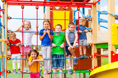 Children at school yard playground climbing together © oksix