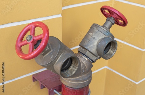 Fire department two way connection standpipe attach to yellow street wall.Fire hydrant, hose connection, fire fighting equipment.