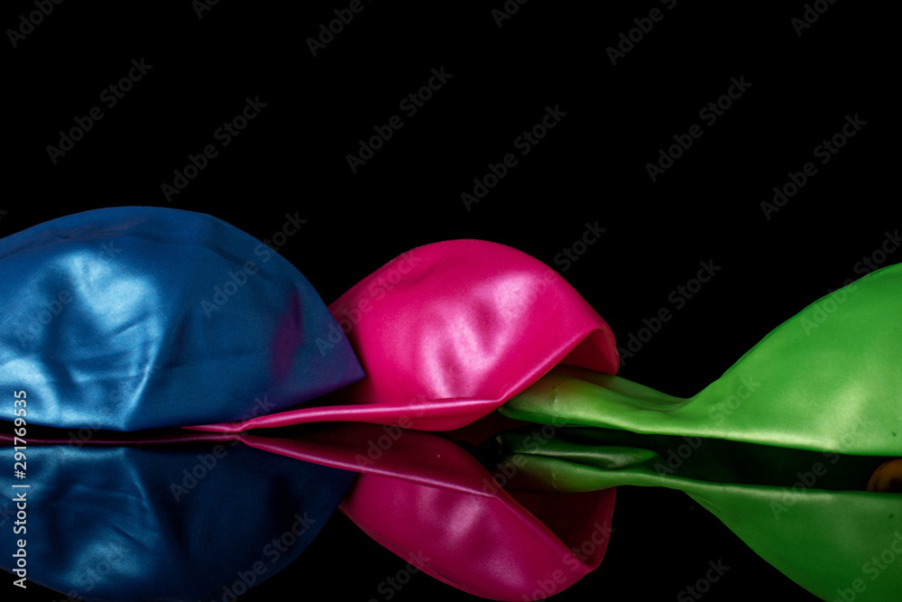Group of three whole latex pastel ballon isolated on black glass