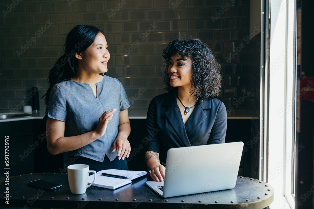 Direct view of young women talking to each other in office Direct view of young women talking to each other in office