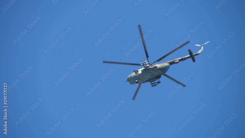 Khaki military chopper hovering low in a blue sky on a sunny day in summer Khaki military chopper hovering low in a blue sky on a sunny day in summer