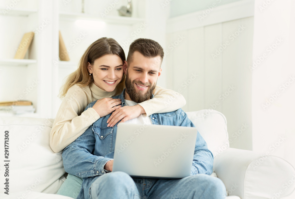 Young couple spending time at home, man using laptop