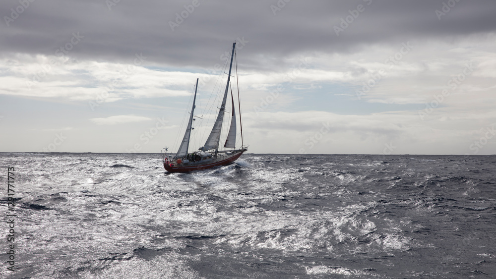 jacht z rozwiniętymi żaglami zmagający się z falami na morzu