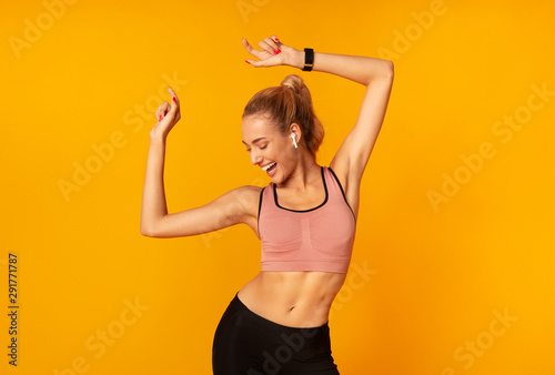 Woman In Wireless Earphones Dancing Listening To Music, Yellow Background photo