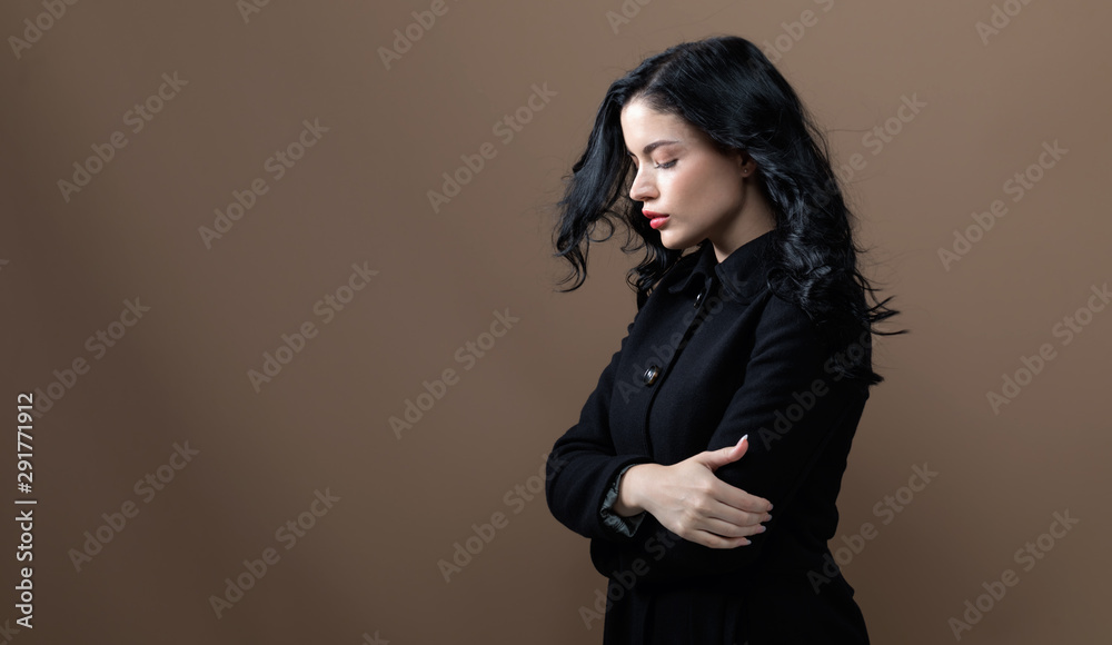 Beautiful young woman in a fashionable coat on a brown background Beautiful young woman in a fashionable coat on a brown background