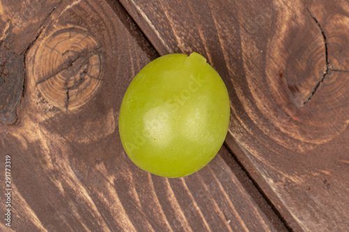 One whole fresh green grape flatlay on brown wood