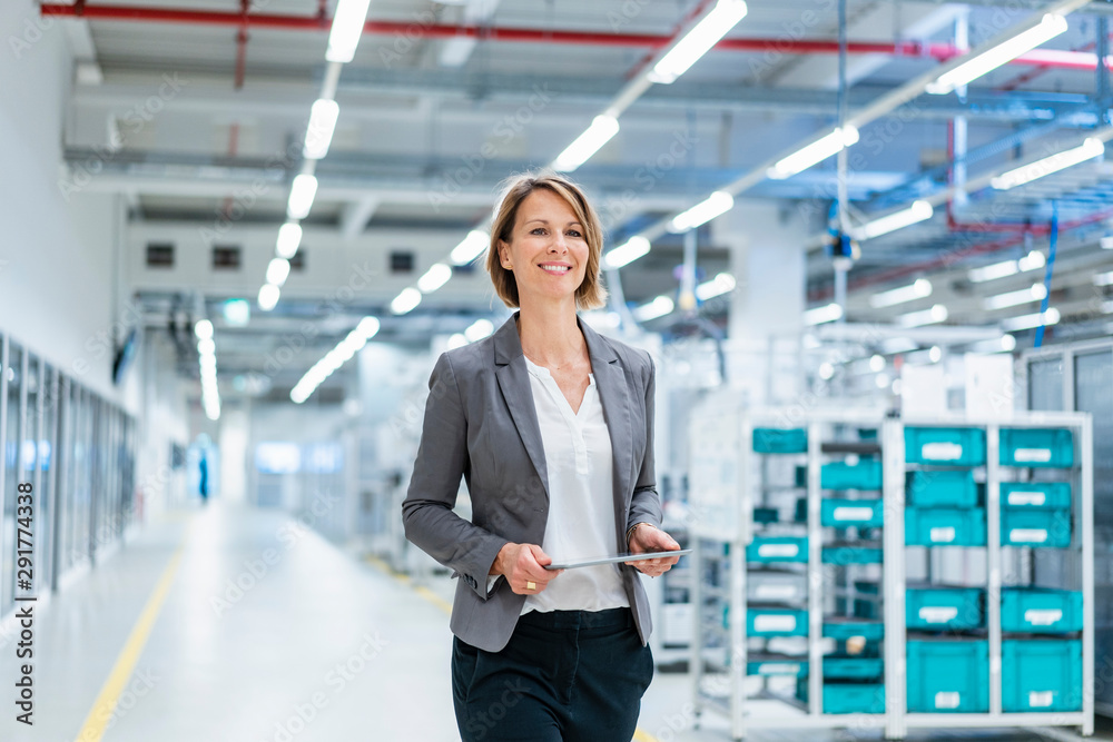 Smiling businesswoman with tablet in a modern factory Smiling businesswoman with tablet in a modern factory