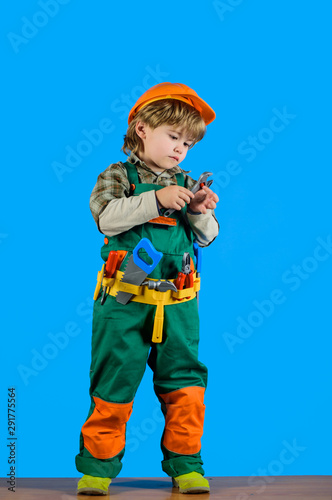 Tools for building. Little kid boy in builder uniform with wrench. Child game. Builder boy in helmet and tools. Kid repairman with tool belt. Work with tools. Repair. Kid boy as builder or repairer.
