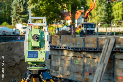 Surveyor equipment (theodolite) on construction site of the airport, building or road with construction machines in background