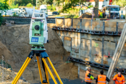 Surveyor equipment (theodolite) on construction site of the airport, building or road with construction machines in background