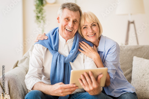 Happy senior couple with digital tablet smiling to camera