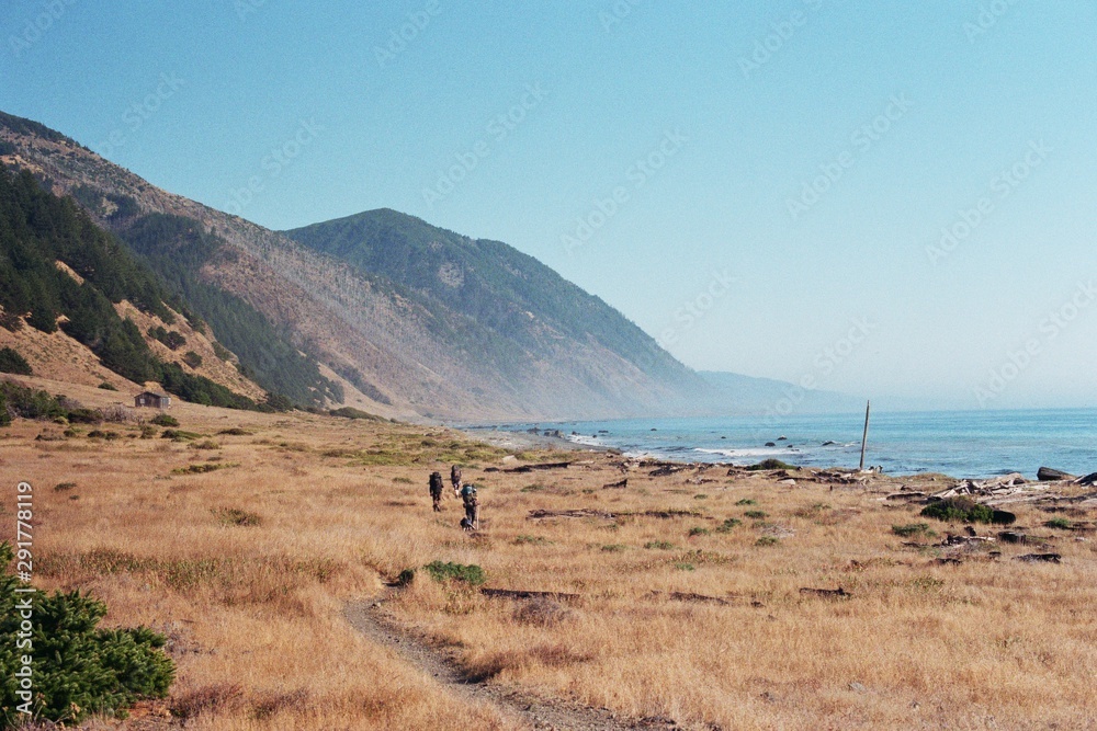 Backpackers walk along coast 