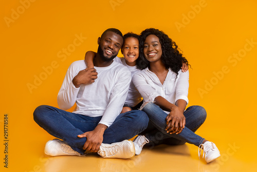 Happy African American Family of Three Over Yellow Background © Prostock-studio